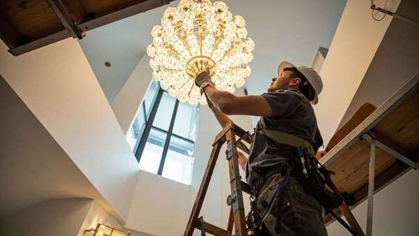 Electrician installing a chandelier-style light fixture
